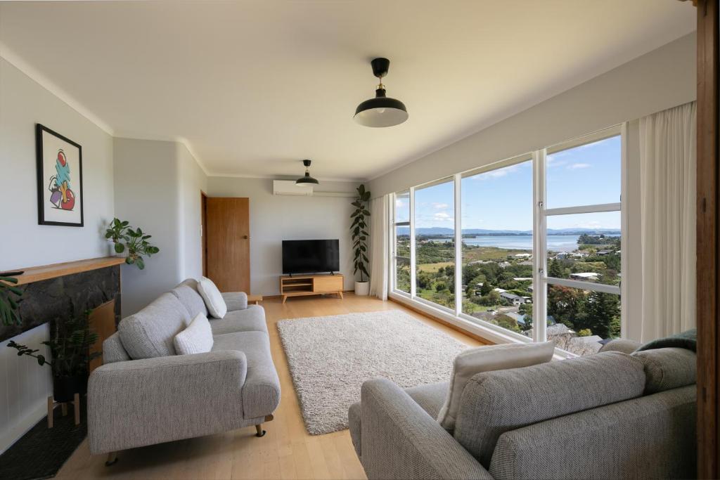 a living room with two couches and a large window at The Hilltop Hideaway in Tauranga