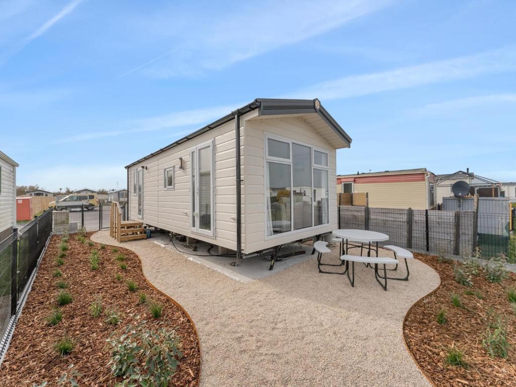 a tiny house with a patio and a table at Chalet in De Haan with terrace in De Haan