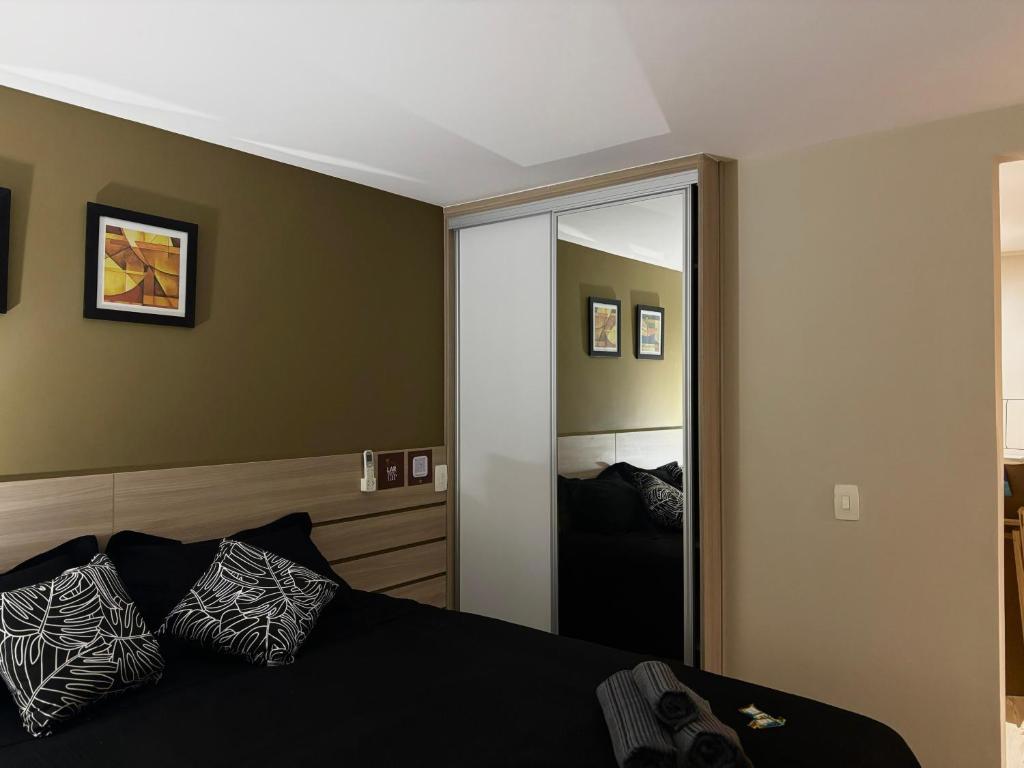 a bedroom with a bed and a large mirror at Flat com Ar, Piscina, Garagem, Cozinha e Wi-Fi in Campo Grande
