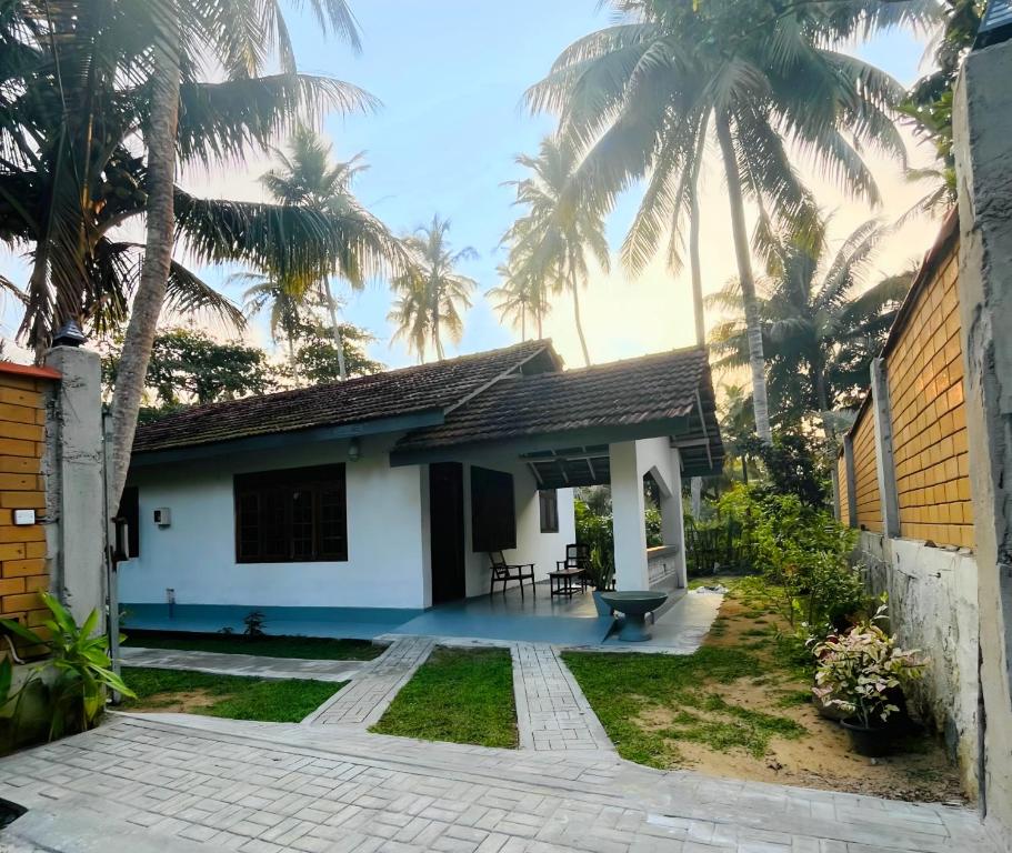 a house with palm trees in front of it at Windy Oasis in Hikkaduwa