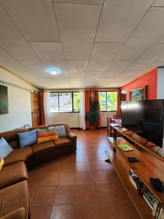 a living room with a couch and a flat screen tv at Comfortable fully equipped apartment just 6 kilometers from Manuel Antonio, with parking and fast WiFi in Quepos