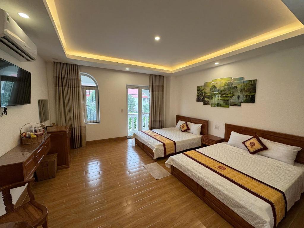a hotel room with two beds and a desk at Hùng Thi Hotel in Cái Răng