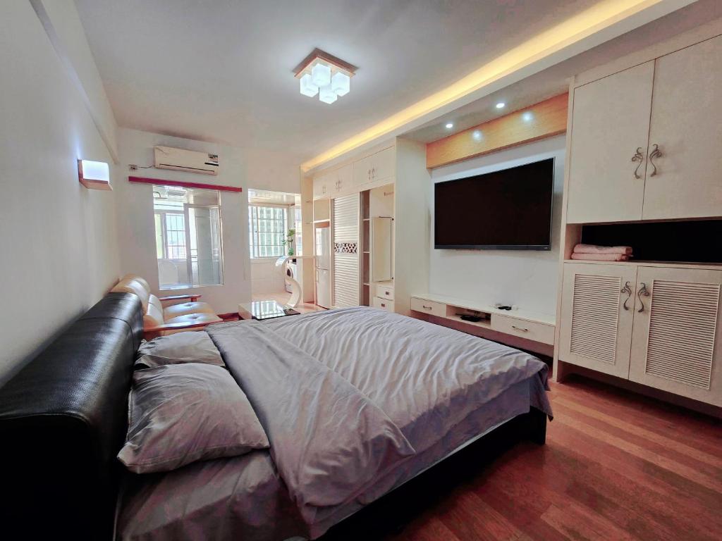 a bedroom with a large bed and a flat screen tv at Ek民宿 in Beihai