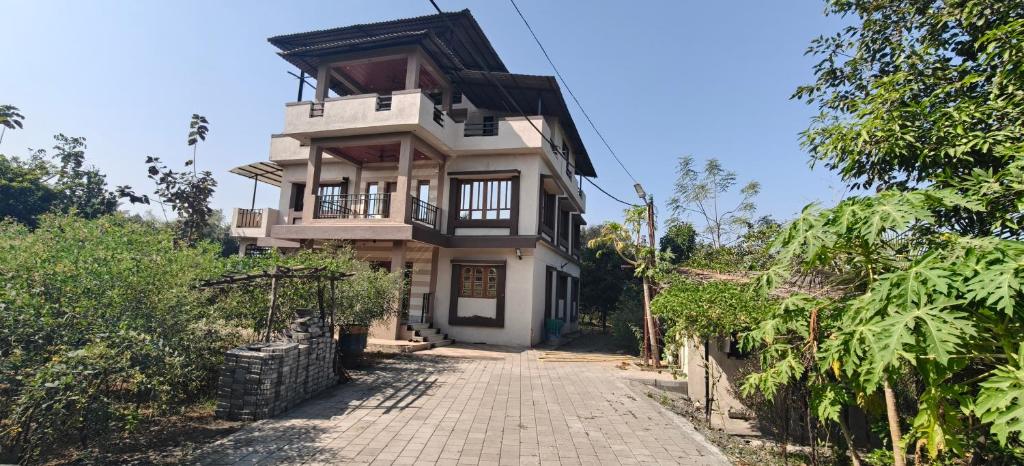 a house on a hill with a dirt road at Vasant Vihar Farm House in Silvassa