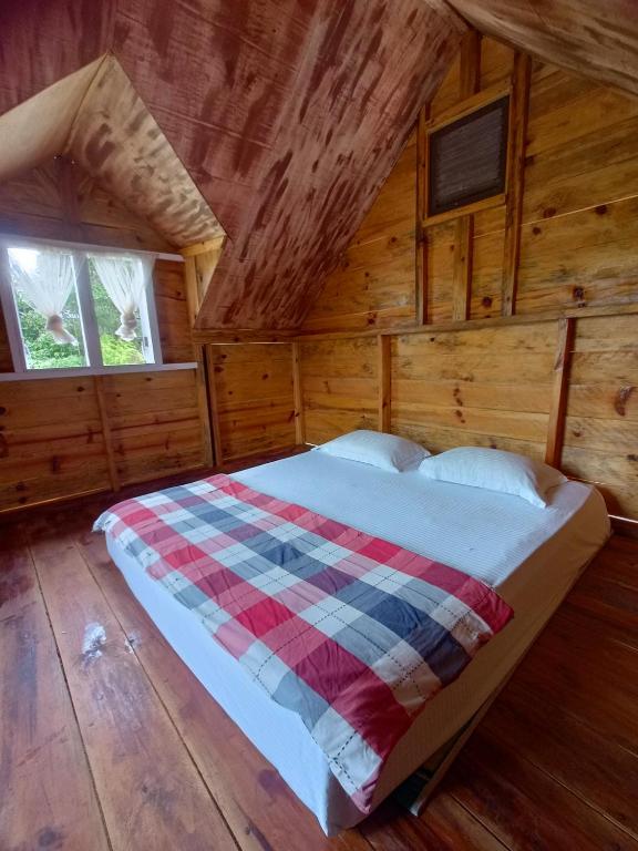 a bedroom with a bed in a log cabin at JE House in Ambarita