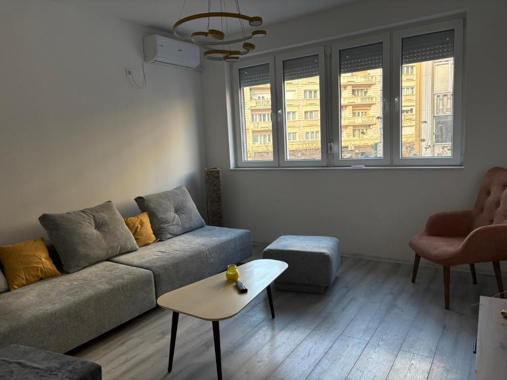 a living room with a couch and two windows at Capital Gate Guest House in Skopje