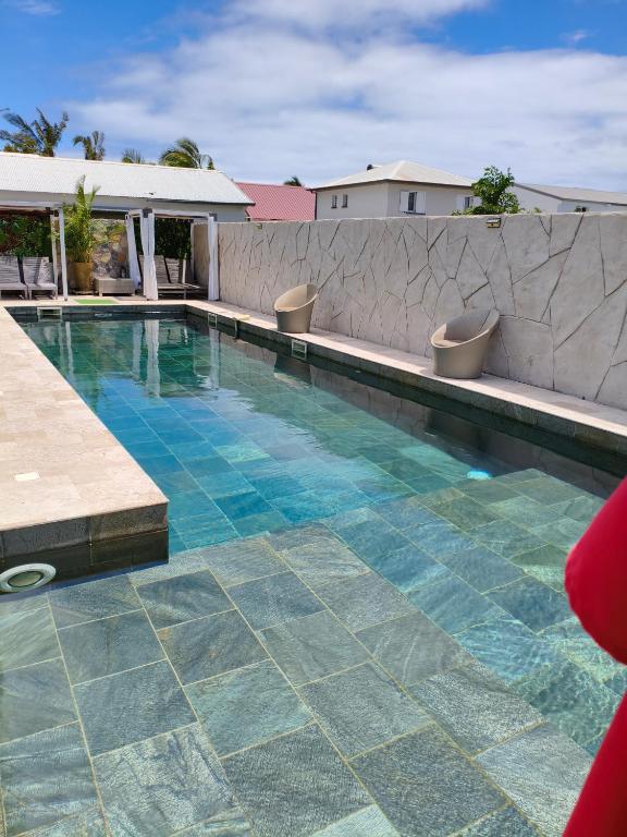 a swimming pool with two chairs next to a wall at Villa Mary Guest House in Saint-André