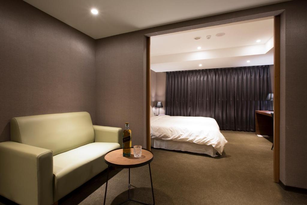 a hotel room with a bed and a couch and a table at Noble Hotel in Taipei