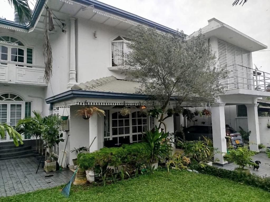 a white house with a tree in the front yard at Dehiwala Holiday Villa in Dehiwala