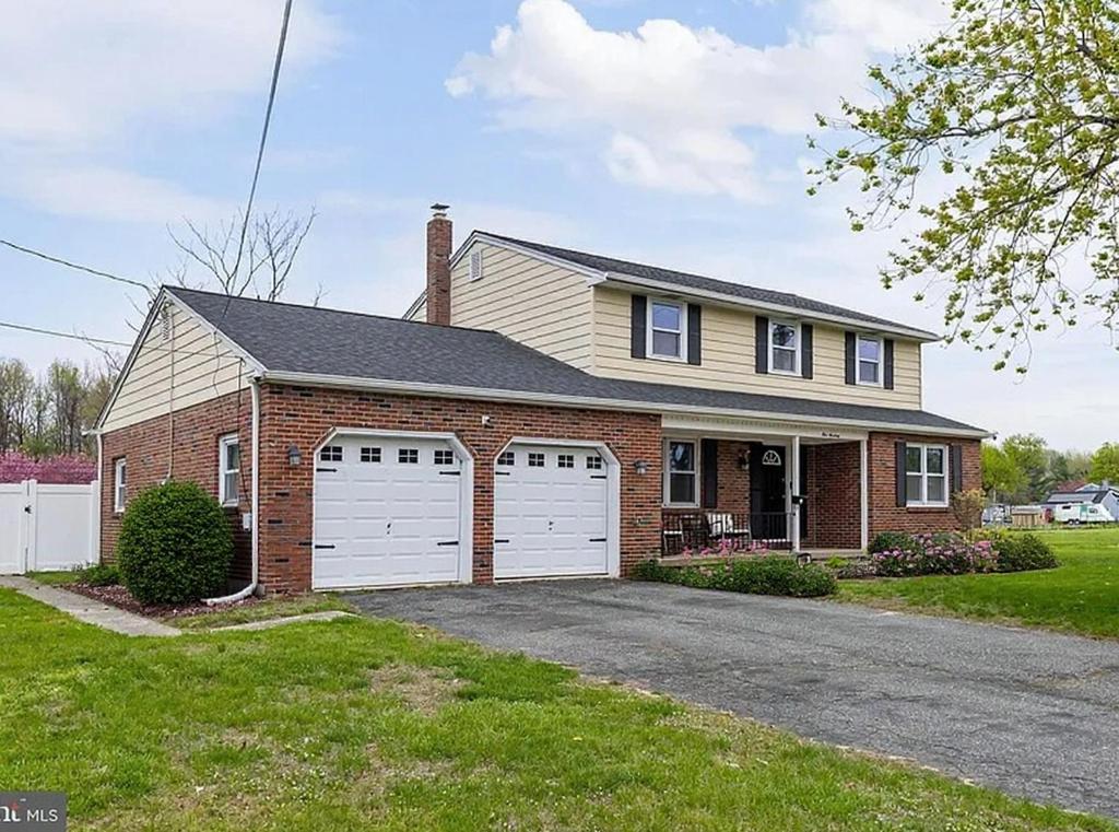 a brick house with two white garage doors at The Carneys Point Cottage in Friendship Station