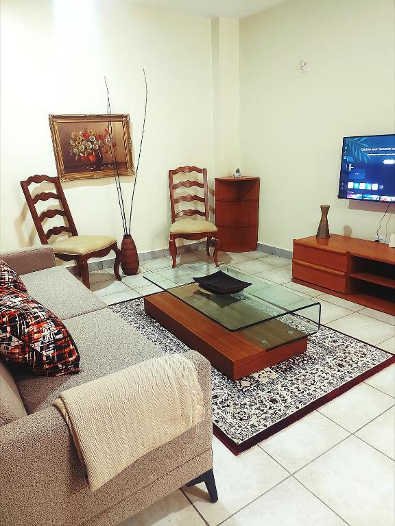 a living room with a couch and chairs and a tv at Casa Rosa in Nanyuki