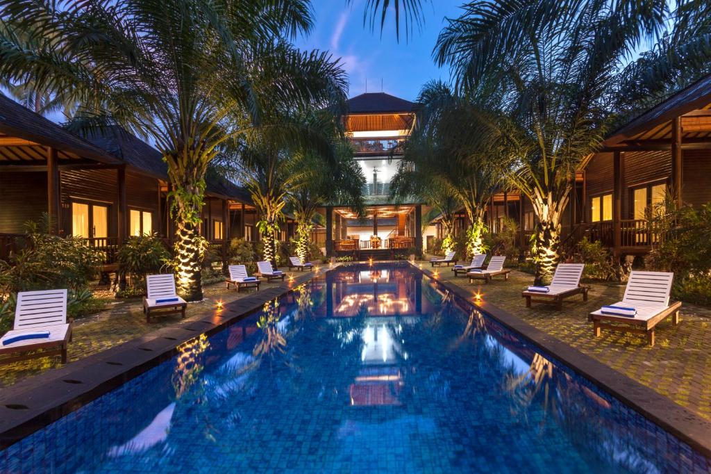 uma piscina num resort com cadeiras e um edifício em Coconut Boutique Resort em Senggigi