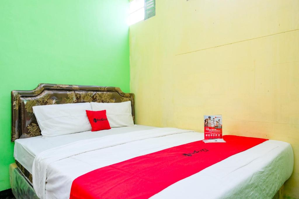 a bedroom with a bed with a red blanket on it at RedDoorz near RSUD Kebumen 2 in Wanasari