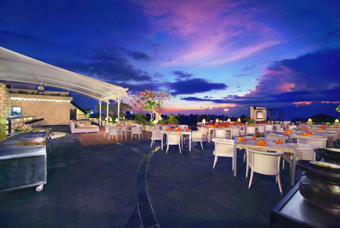 a group of tables and chairs on a patio at night at Kuta Reef Apartments in Kuta