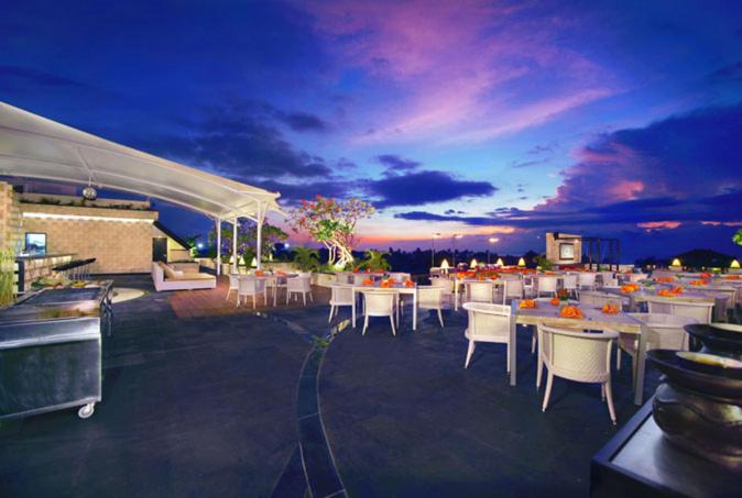 Un grupo de mesas y sillas en un patio por la noche. en Kuta Reef Apartments, en Kuta
