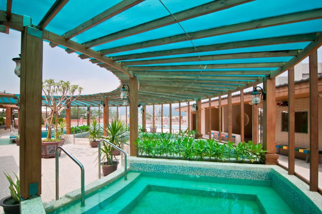 an outdoor swimming pool with a wooden pergola and a swimming poolvisor at JinShan Sakura Bay Hot Spring Hotel in Jinshan