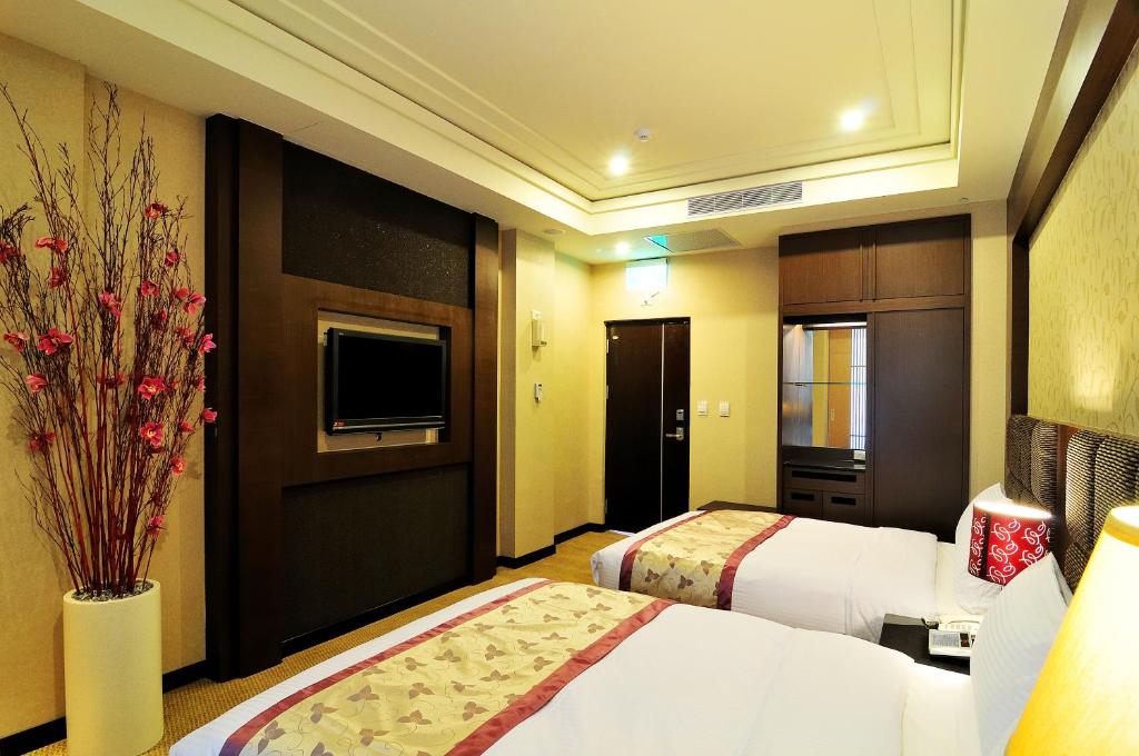 a hotel room with two beds and a television at JinShan Sakura Bay Hot Spring Hotel in Jinshan