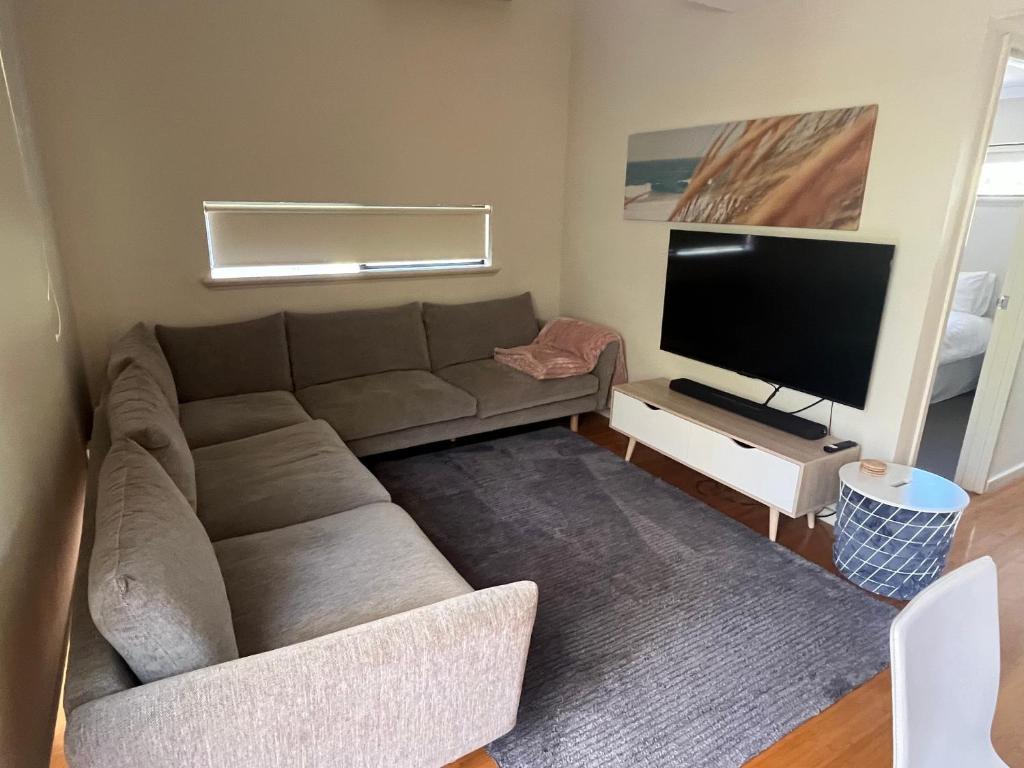 a living room with a couch and a flat screen tv at 2 bed self-contained Beach Shack in Preston Beach