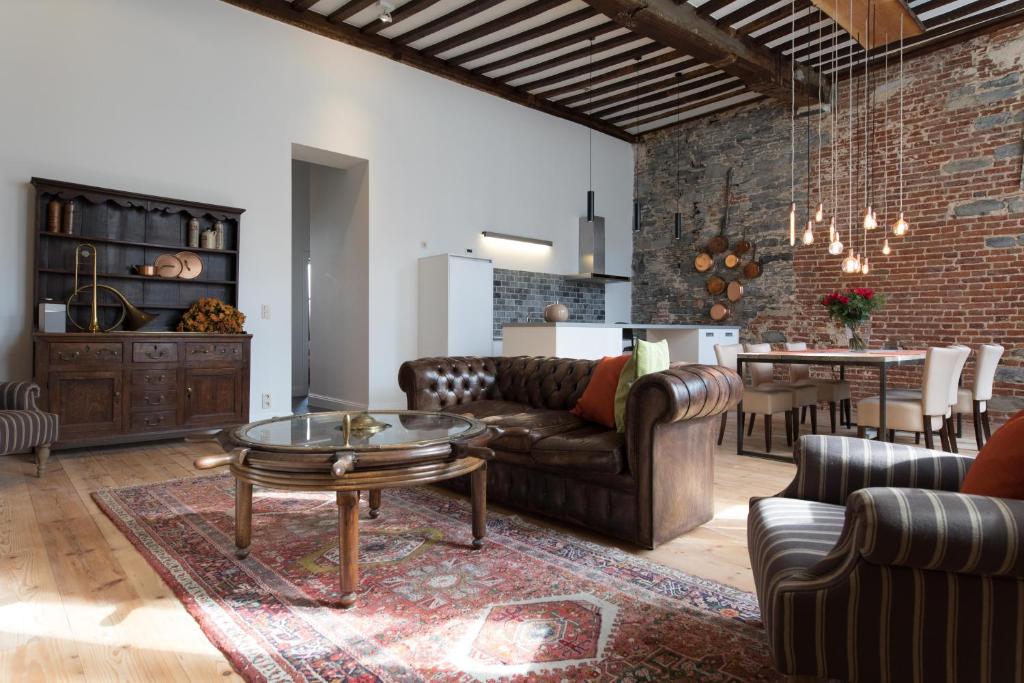 uma sala de estar com mobiliário de couro e uma parede de tijolos em Hof Van Spanje em Gent