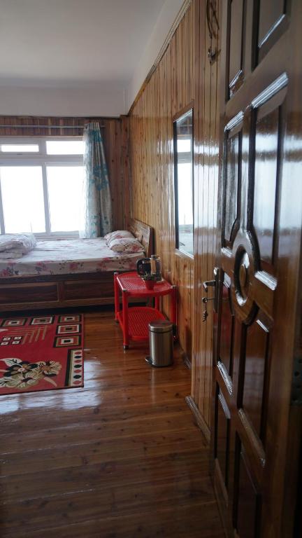 a room with a bed and a door with a table at Tranquil Retreat Homestay in Ghum