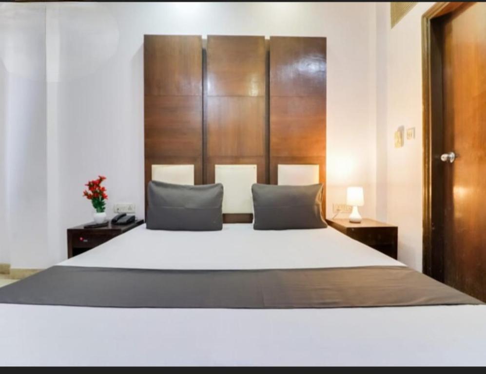 a bedroom with a large white bed with a wooden headboard at Hotel Parth Palace in New Delhi