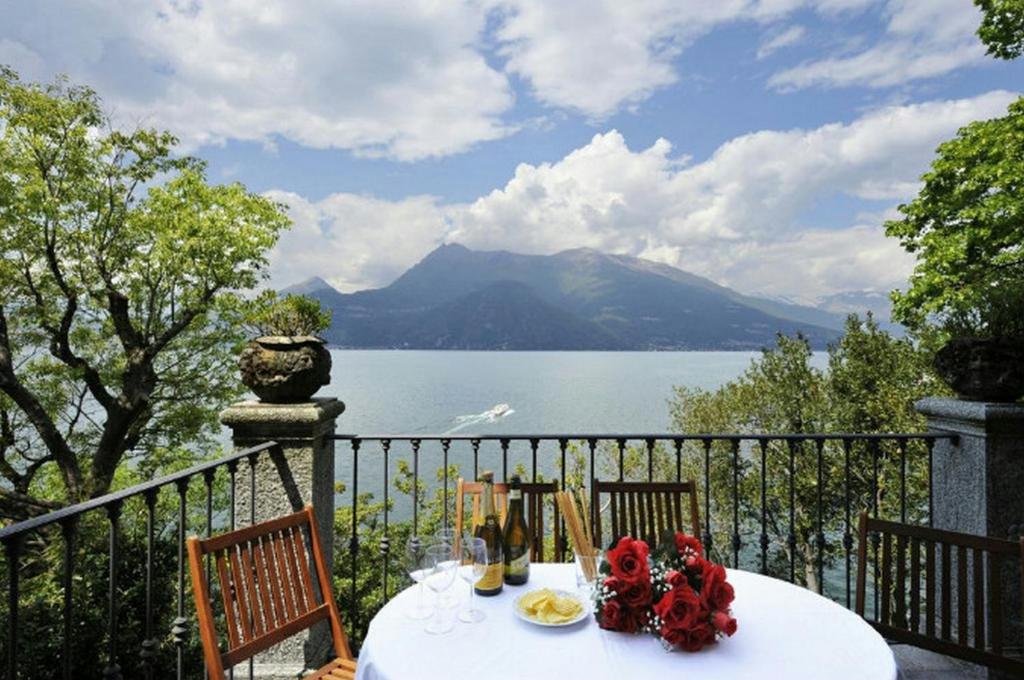 una mesa con flores en un balcón con vistas al lago en Villa Lucia Varenna, en Varenna