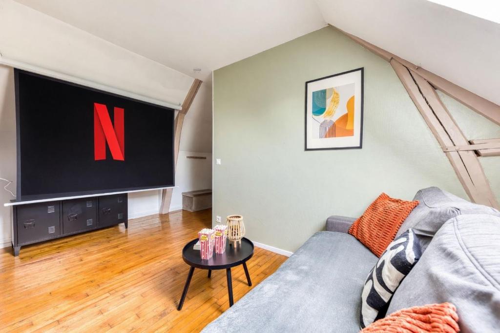 a living room with a couch and a large screen at Cocon Forestier - Home cinema- Netflix free - Proche aéroport Beauvais, Chantilly, forêt de Hez-Froidmont, parking public gratuit, Wifi & Netflix in Clermont