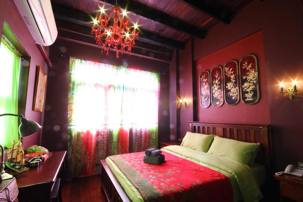 a bedroom with a bed with a red blanket and a chandelier at Baan Nai Nakhon in Songkhla