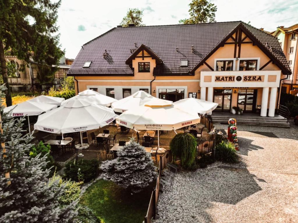 a restaurant with white umbrellas in front of a building at Matrioszka Pokoje Hotelowe in Gołdap