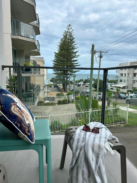 a balcony with a blanket on a chair and a window at Pleasant View Apartment - Ocean View in Caloundra