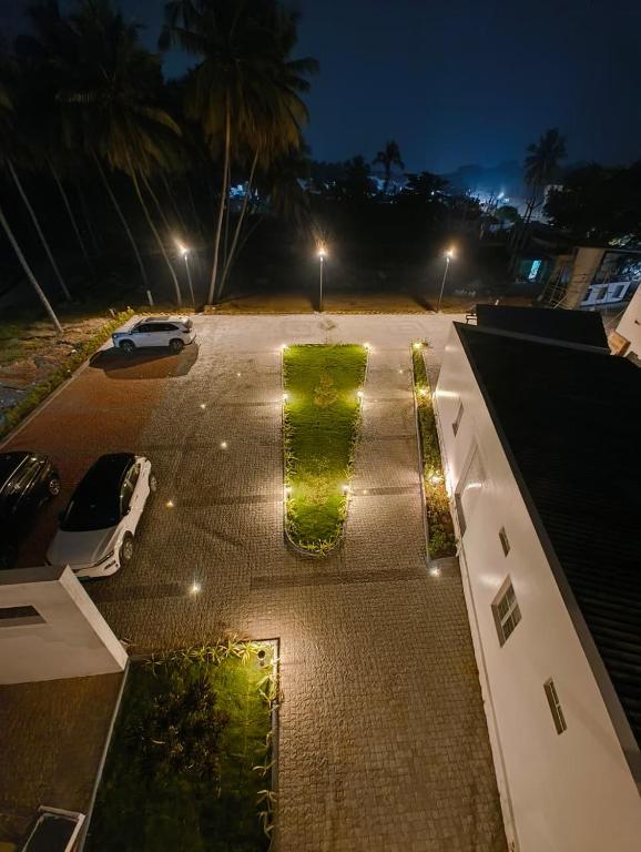a parking lot at night with a green hedge at Arthana Residency Hotel in Mānuppatti