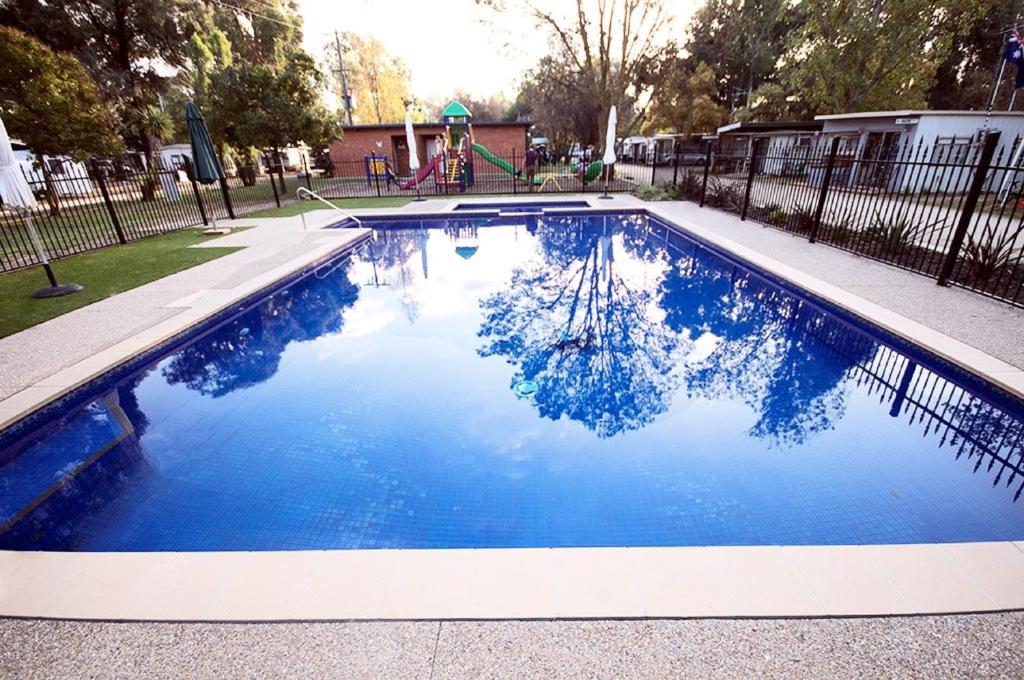 a swimming pool with blue water and a playground at Nagambie Caravan Park & Motel in Nagambie