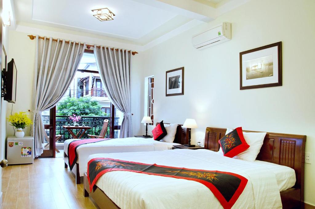 a hotel room with two beds and a balcony at An Hoi Town Homestay in Hoi An