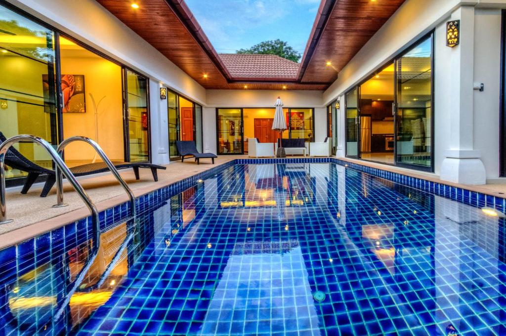 a swimming pool with blue tiles in a house at Chambertin Villa by G Estate in Rawai Beach