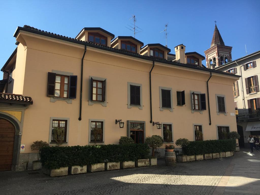ein großes weißes Gebäude mit schwarzen Fenstern auf einer Straße in der Unterkunft Antica Trattoria dell'Uva in Monza