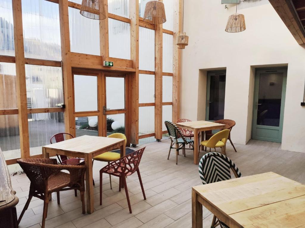 a restaurant with wooden tables and chairs and windows at Le Mandragot - Séjour en Aspe in Bedous