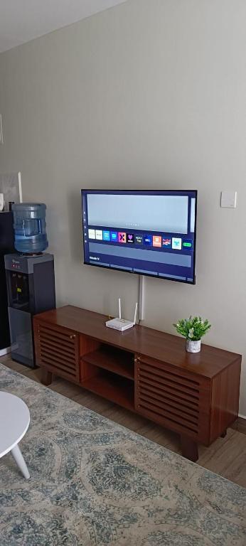 a flat screen tv sitting on top of a wooden entertainment center at BlueByMis Studio Apartment in Muchatha