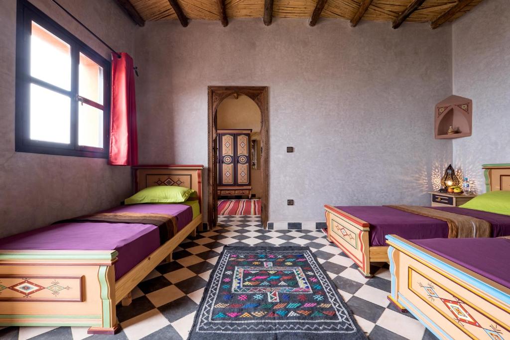 a bedroom with two beds and a checkered floor at Le Nid d'Aigle in Mirleft