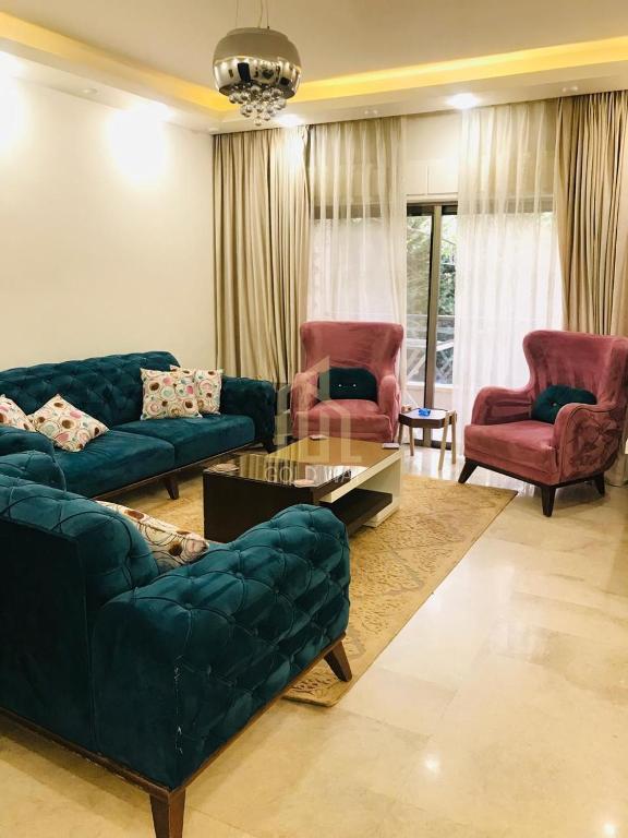 a living room with a couch and two chairs and a table at Chic 2-Bedroom - Fully Furnished in Amman