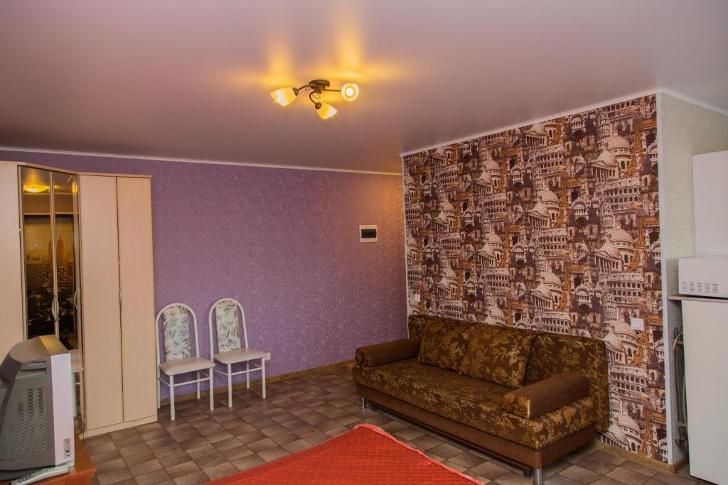 a living room with a couch and a brick wall at Gostevay kvartiry na Melnikayte 101 in Tyumen