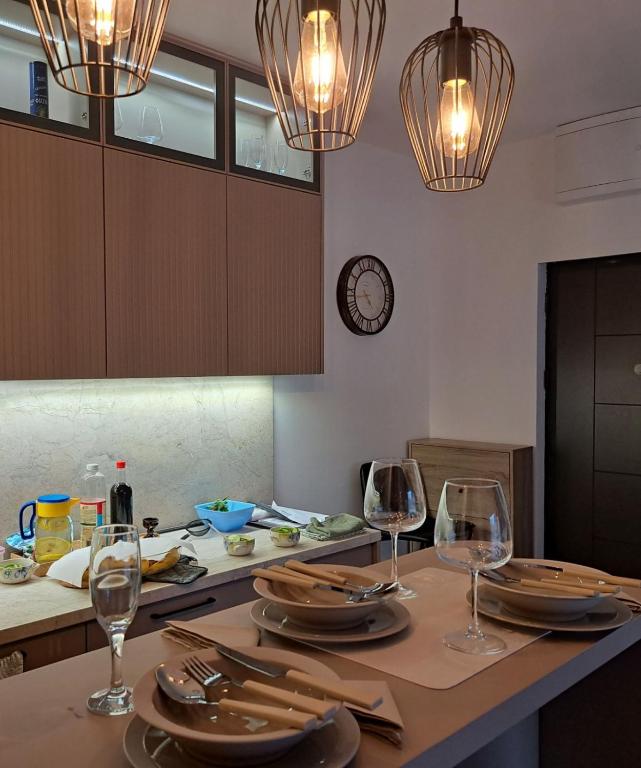 a dining table with wine glasses and a clock on the wall at Avram in Vrnjci