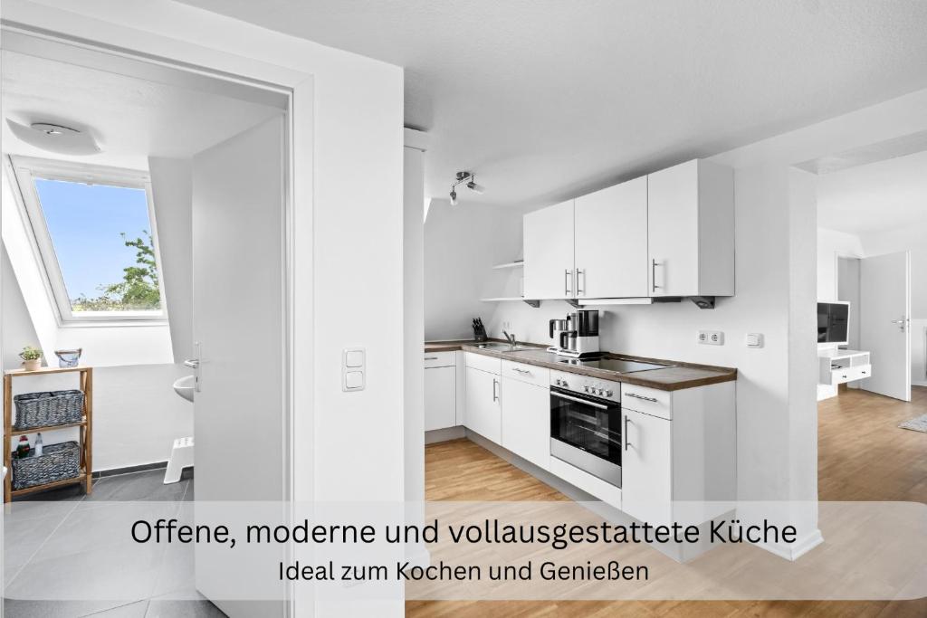 an open kitchen with white cabinets and a window at Moderne Ferienwohnung in Strandnähe - Urlaubsträume am Meer in Neue Tiefe Fehmarn