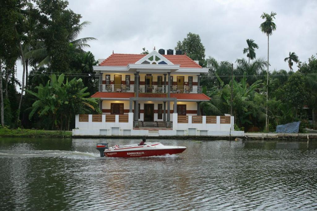 a boat in the water in front of a house at Mango Kerala Homes in Kumarakom