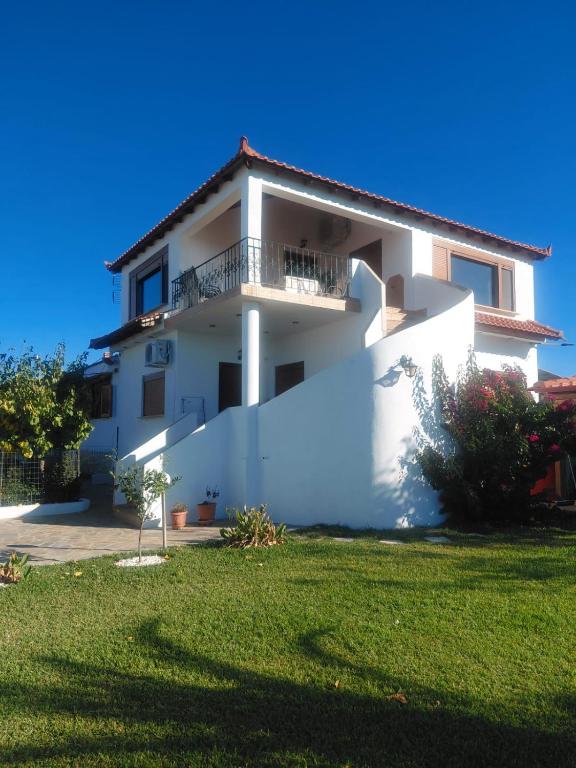 a white house with a green lawn in front of it at Vista Mare in Nea Irakleia
