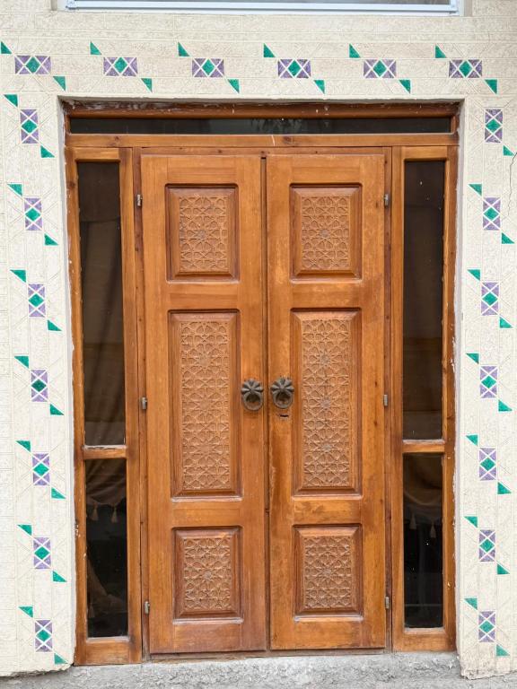 a wooden door in front of a building at Al-Adl Guest House in Bukhara