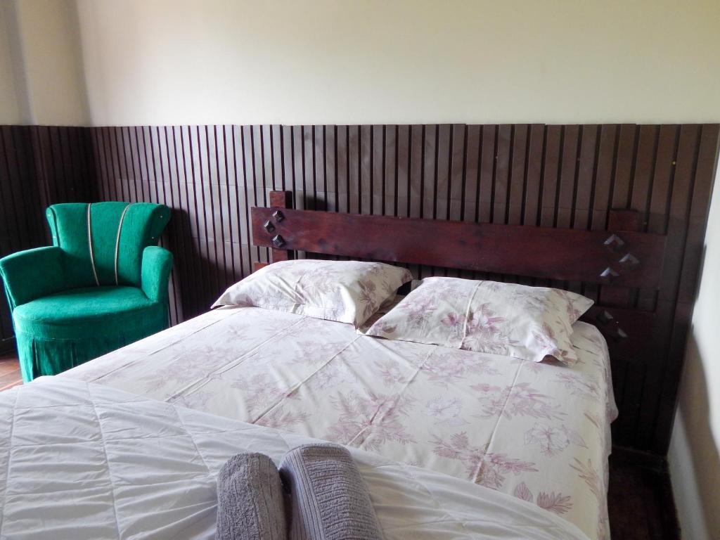 a bedroom with a bed and a green chair at Casa de Mariazinha in Ouro Preto