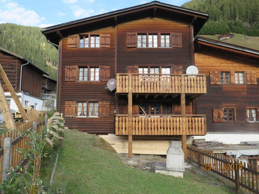 a large wooden house with a deck in front of it at Adli in Disentis