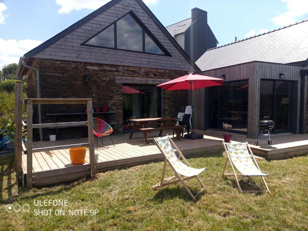 a patio with two chairs and a table and an umbrella at Ti Forn - Les fours à pain in Dinéault