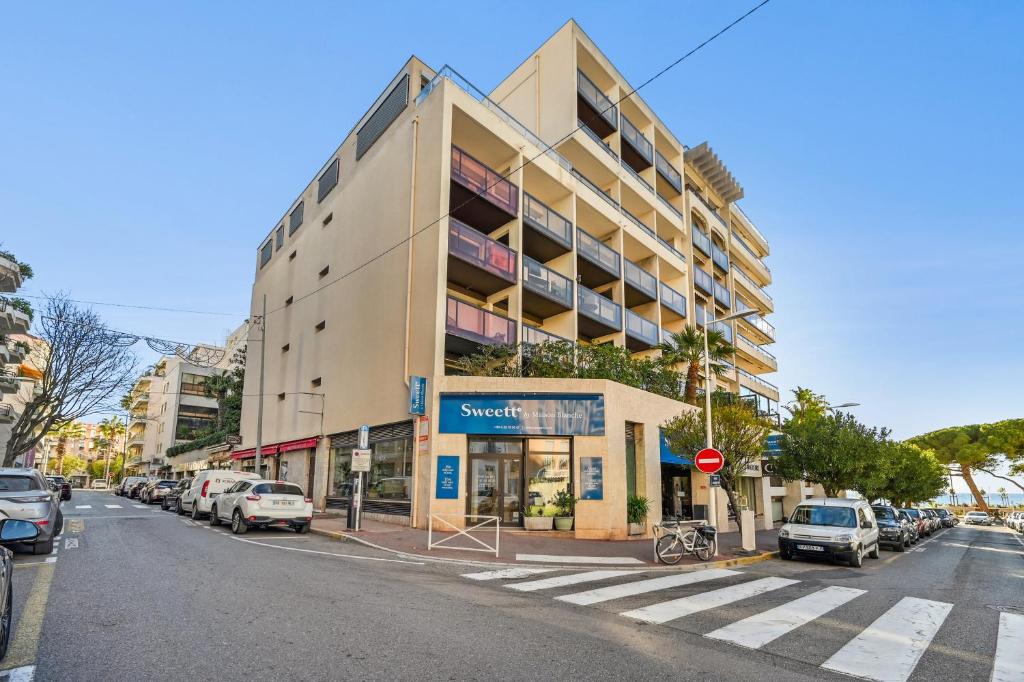 a building on a street with cars parked on the street at Sweett - Maison Blanche in Juan-les-Pins