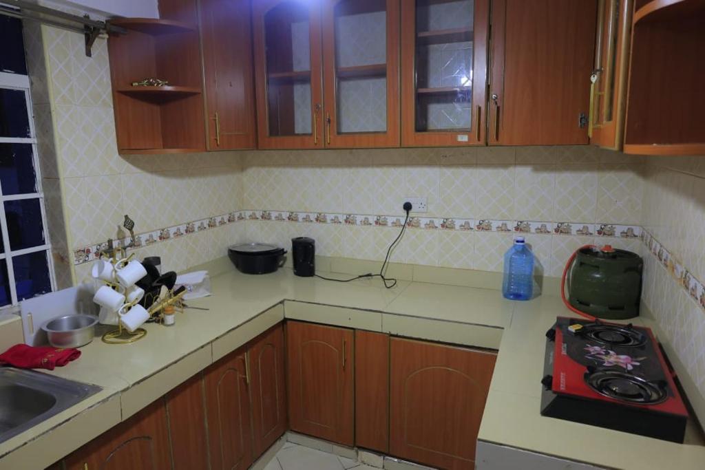 a kitchen with wooden cabinets and a red appliance on the counter at Amani Home in Kisii